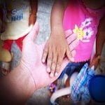 close up image of adult and child hand in hand