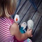 toddler girl sitting on the floor looking at stuffed dolls